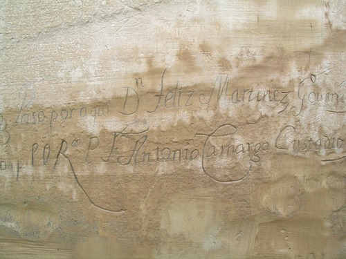 An inscription appears on a rock. It reads: "Year of 1716 on the 26th of August passed by here Don Feliz Martinez, Governor and Captain General of this realm to the reduction and conquest of the Moqui (Hopi) and [with him] the reverend Father Friar Antonio Camargo, Custodian and ecclesiastical judge."