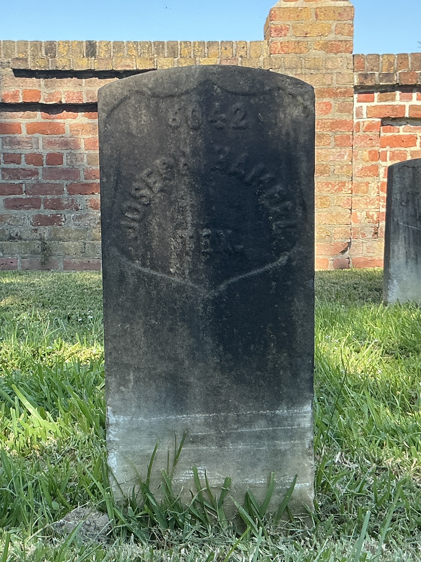 Front of historic upright marble headstone with recessed shield face.