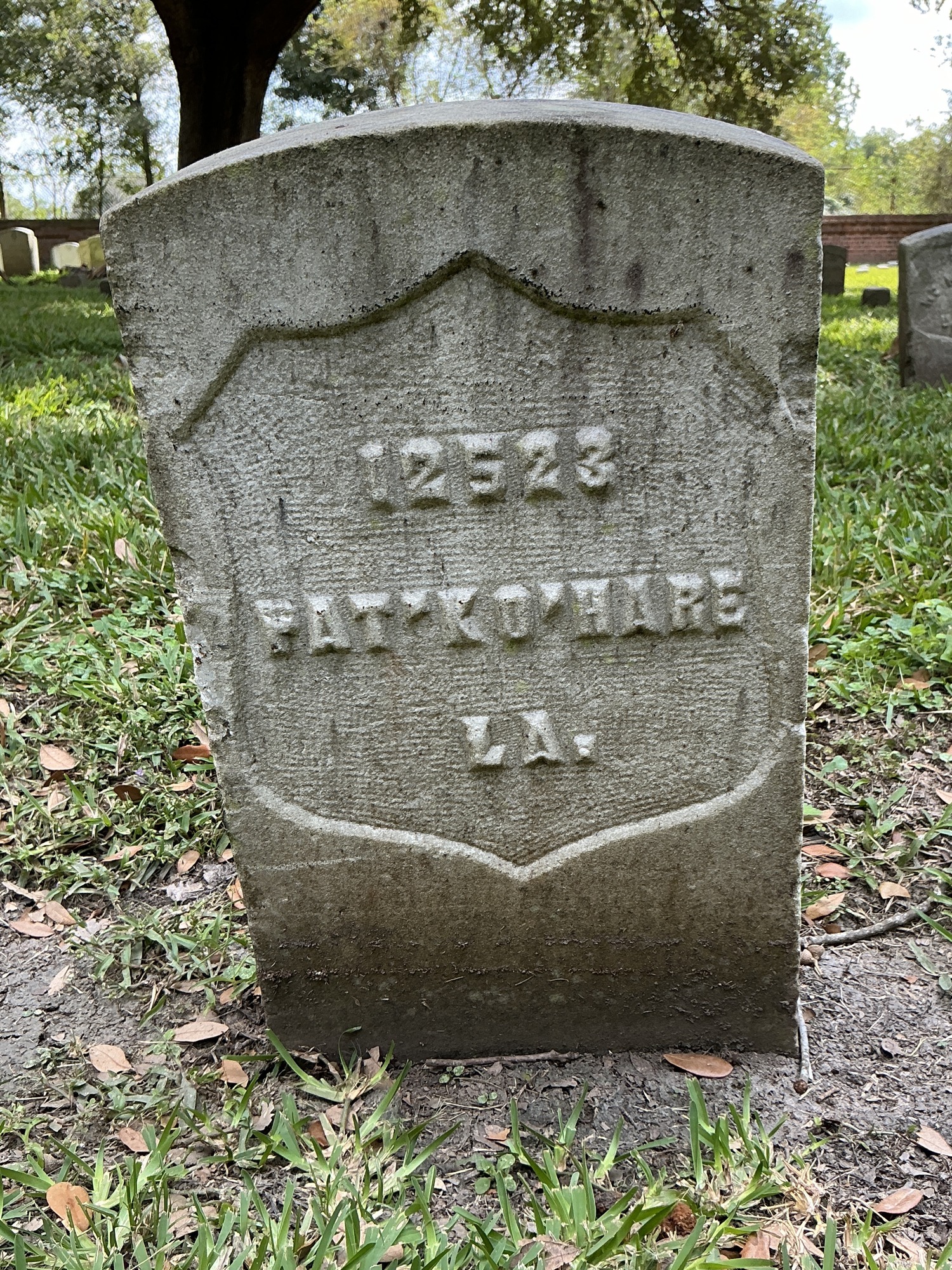 Front of historic upright marble headstone with recessed shield face.