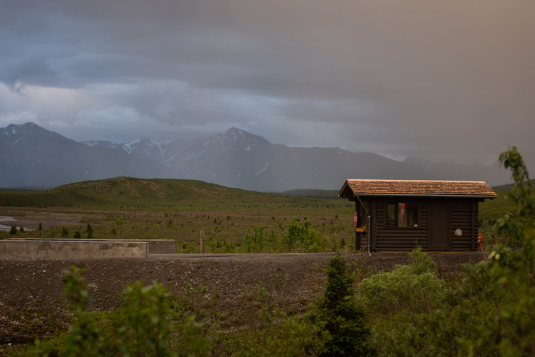 small wooden building on a road near a valley 
