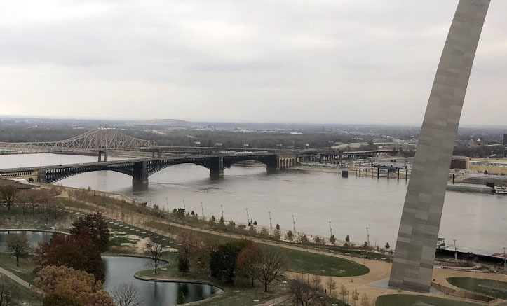 Looking down upon the Arch grounds with the north leg of the Arch at the right side of the image and the Eads Bridge at the top with the Mississippi River running through the photo
