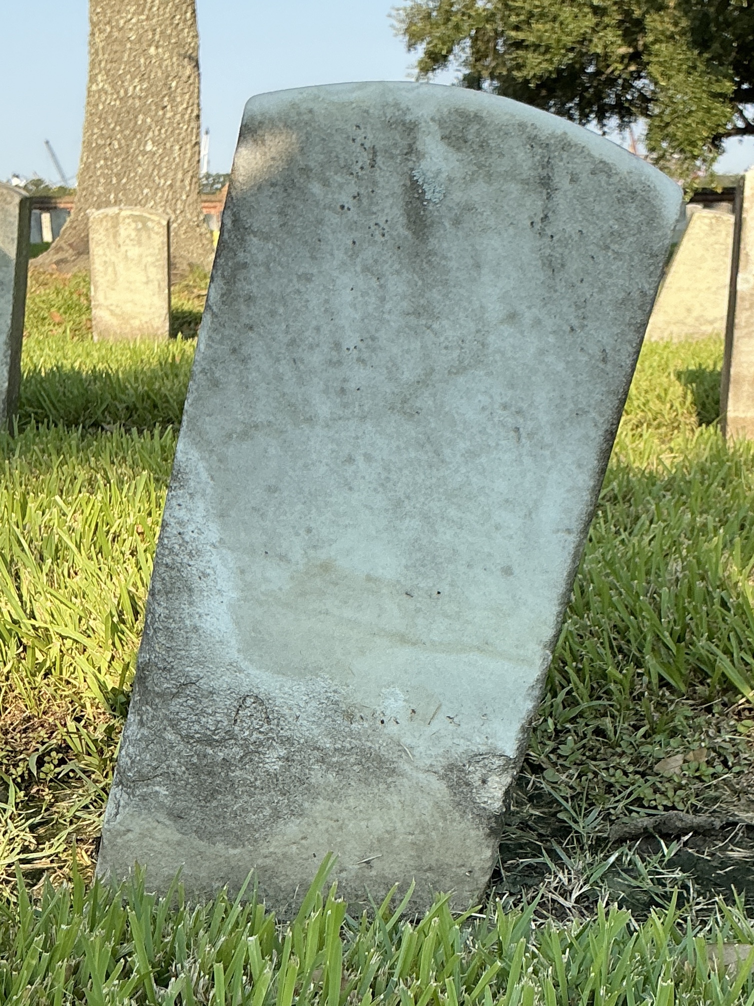 Back of historic upright marble headstone with recessed shield face.