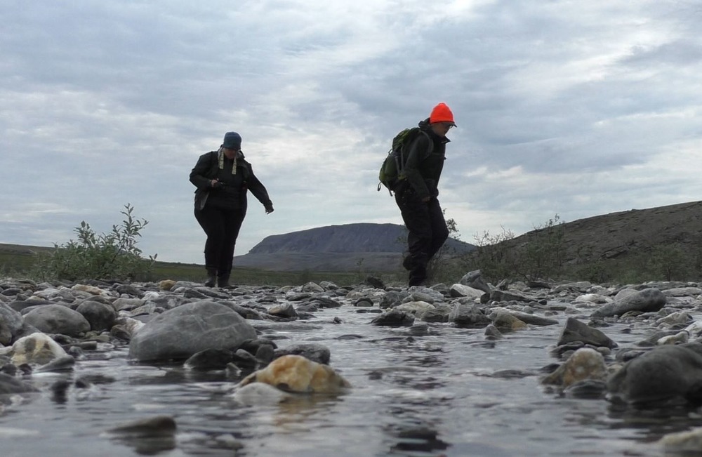 Two hikers cross a small stream