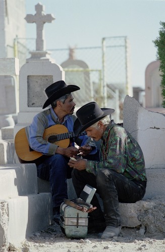 Men in cemetery at a Day of the Dead celebration.