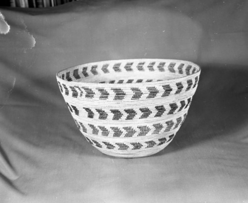 Mrs. Donald Segerstrom Collection. Object: Western Mono basket purchased from a Miwok. Dimensions: 14 1/2 x 8". Materials: sedgeroot, redbud, fern root, and bunchgrass. Technology: noninterlocking stitch, leftward coil direction, outside workface, fag ends trimmed on work face, moving ends trimmed on interior, tight spiral start with overstitching in center. Collection History: Purchased from Mrs. Mary Longfellow Poncho (Maggie Longfellow Antonini's mother) Photographed by Michael Dixon, January 1983. Catalogued by Craig Bates and Barbara Beroza. Yosemite Collections, National Park Service.