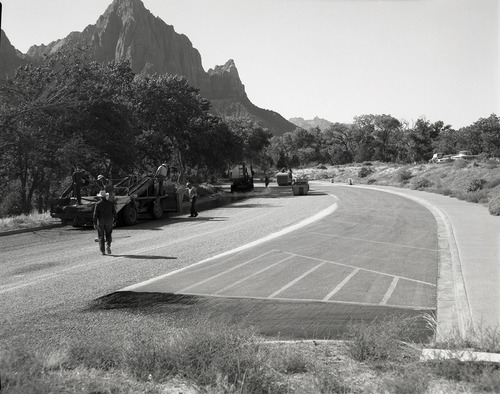 Men operating sealcoating machine while sealcoating parking area in Zion.