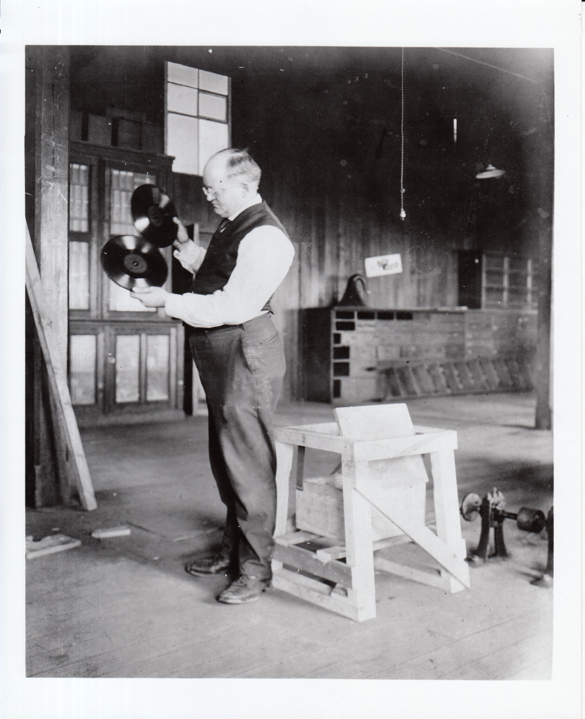 Charles Dally examining two disc phonograph records after "bump" test on third floor of Laboratory Building 5.