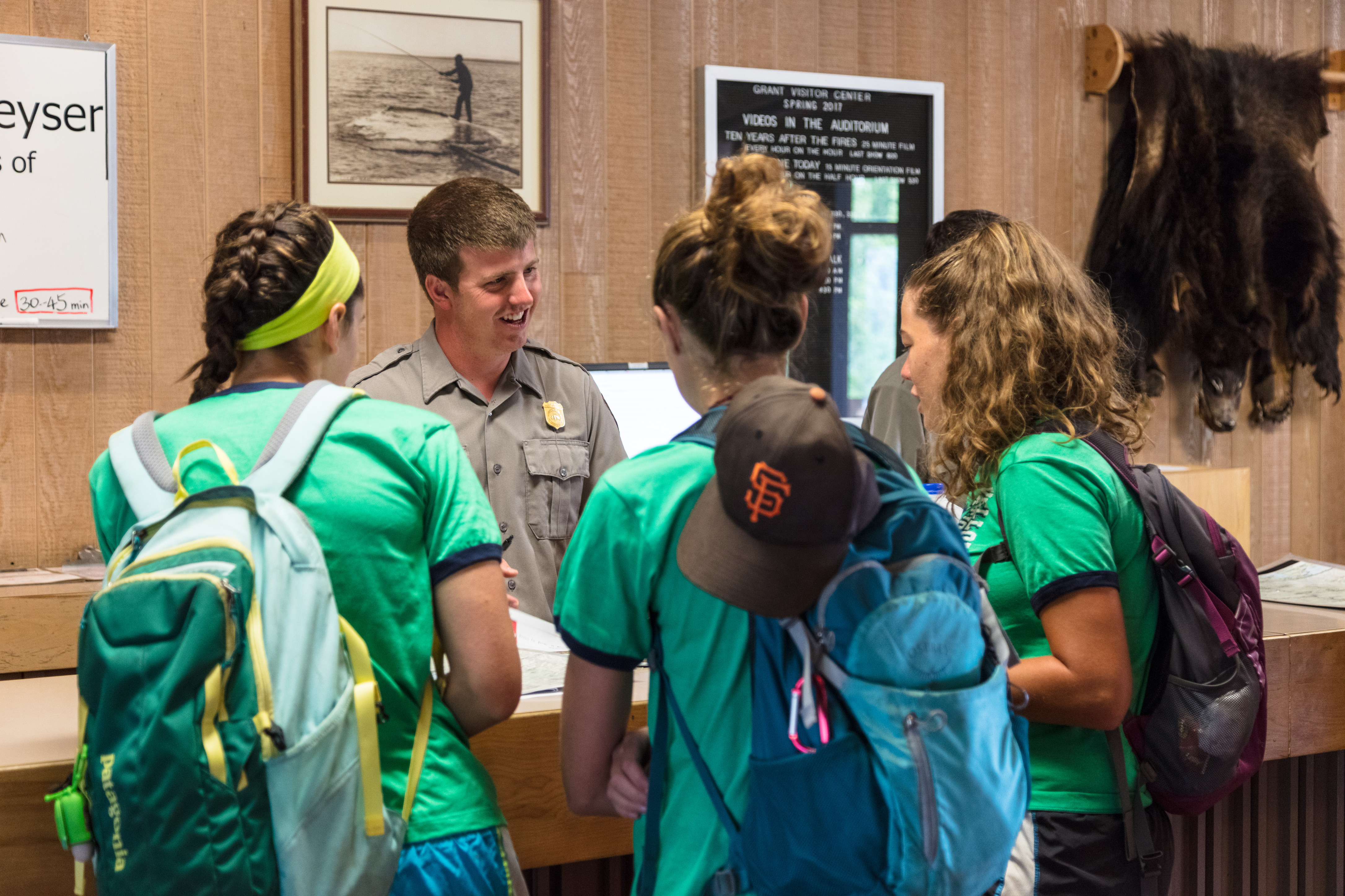 A male ranger talks with three woman over a counter top in a visitor center.
