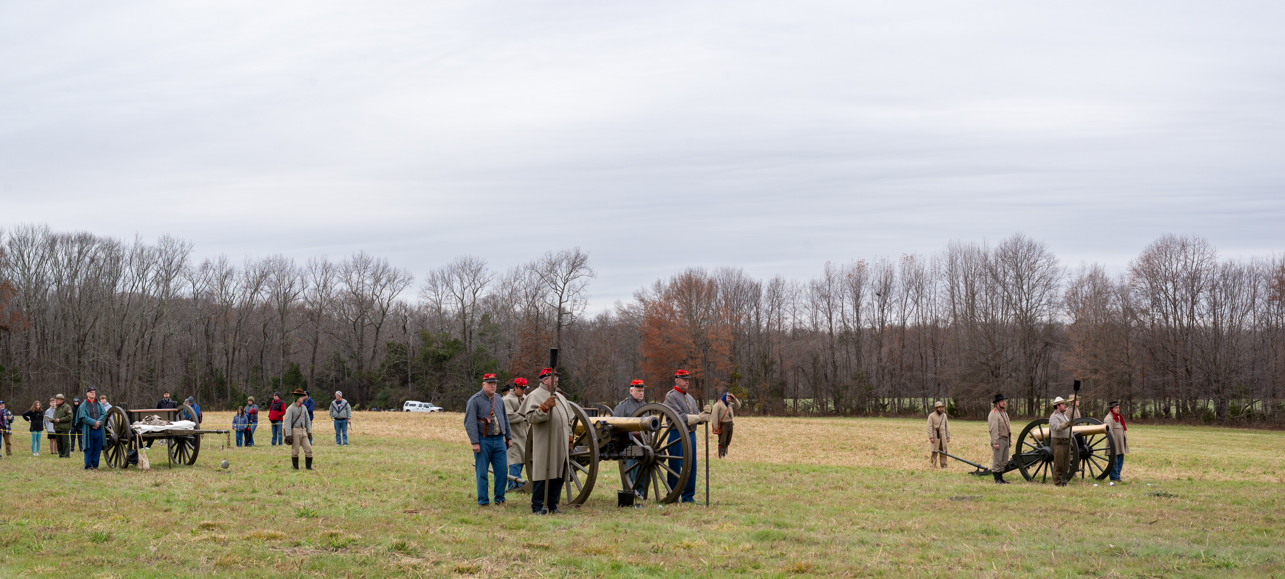 Panoramic image of living historians dressed as Confederate artillerymen near two cannons pointed at a wide open field.