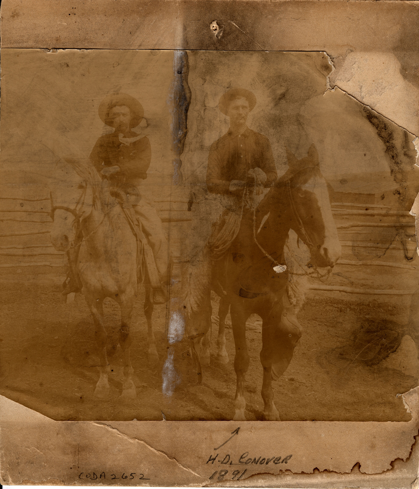 Heavily faded sepia toned photograph of two men on horses in front of a wooden fence. Handwritten text with arrow at the bottom reads: "H.D. Conover 1891" and "CODA 2652"