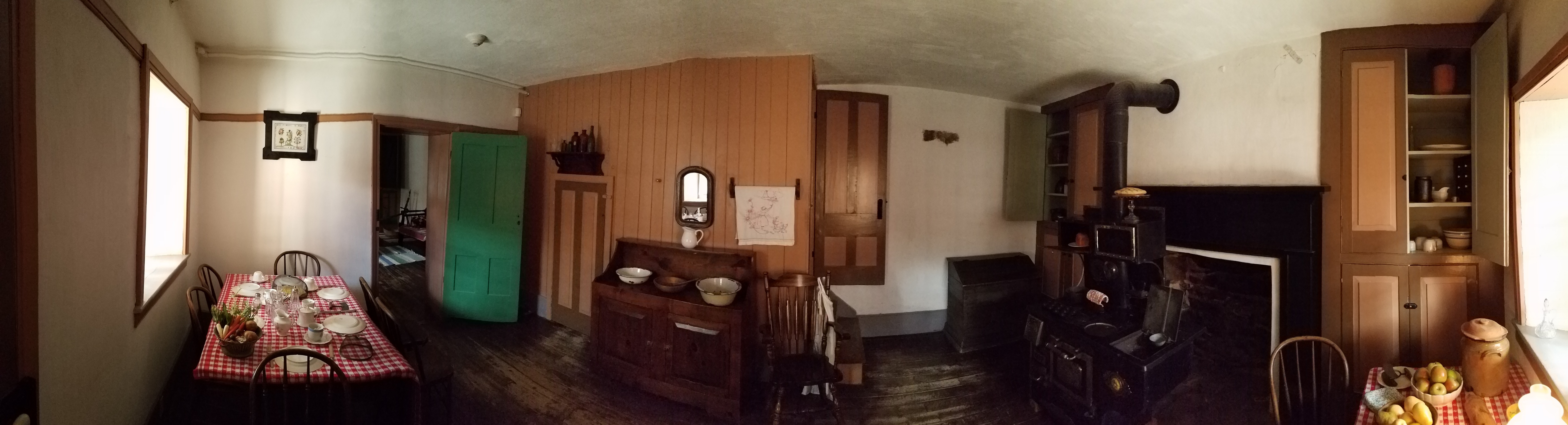 Panorama of the Kitchen in the Fort, there is a set table to the left and a large Arcadian wood stove to the right