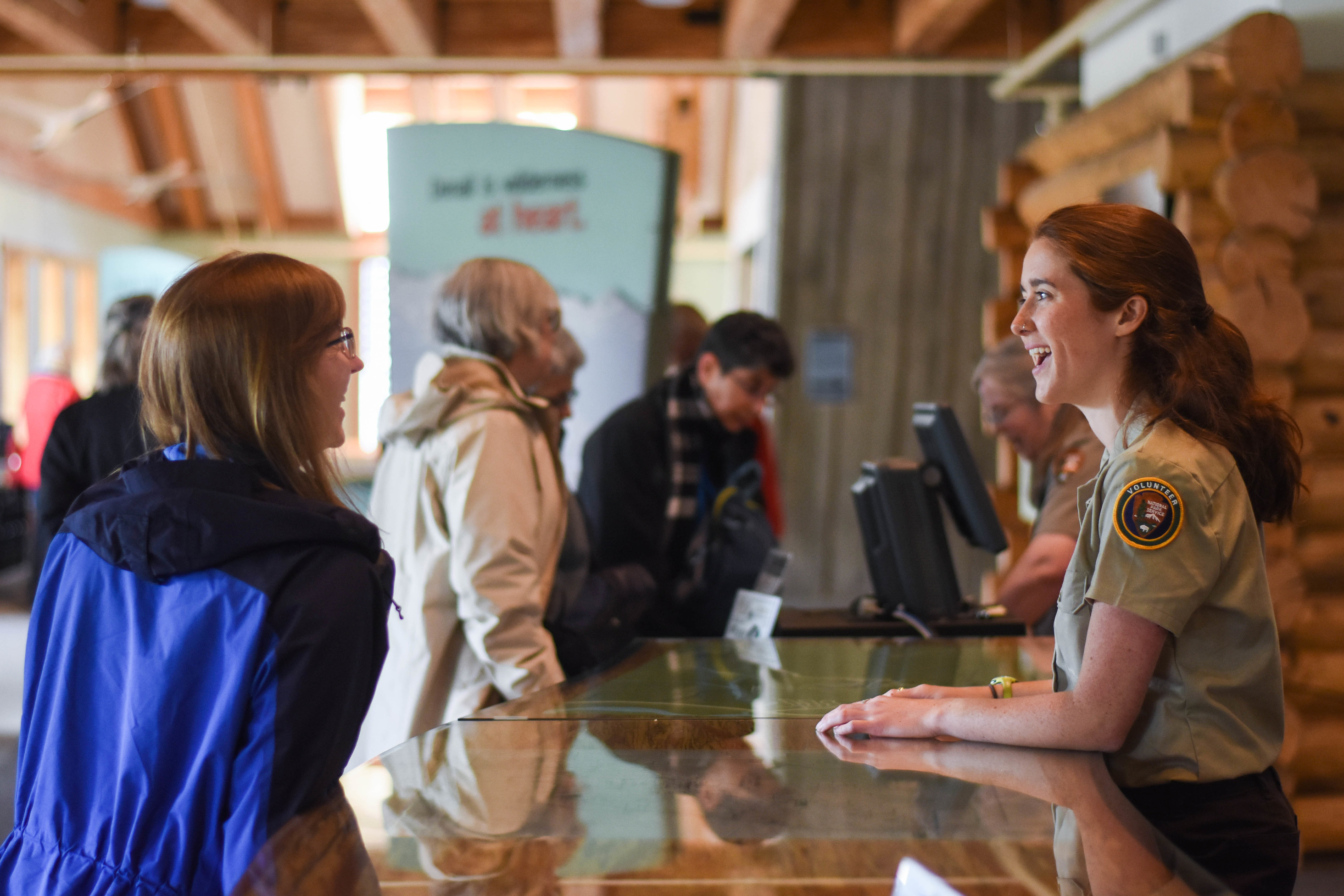 people talking to a ranger and uniformed volunteer at a desk