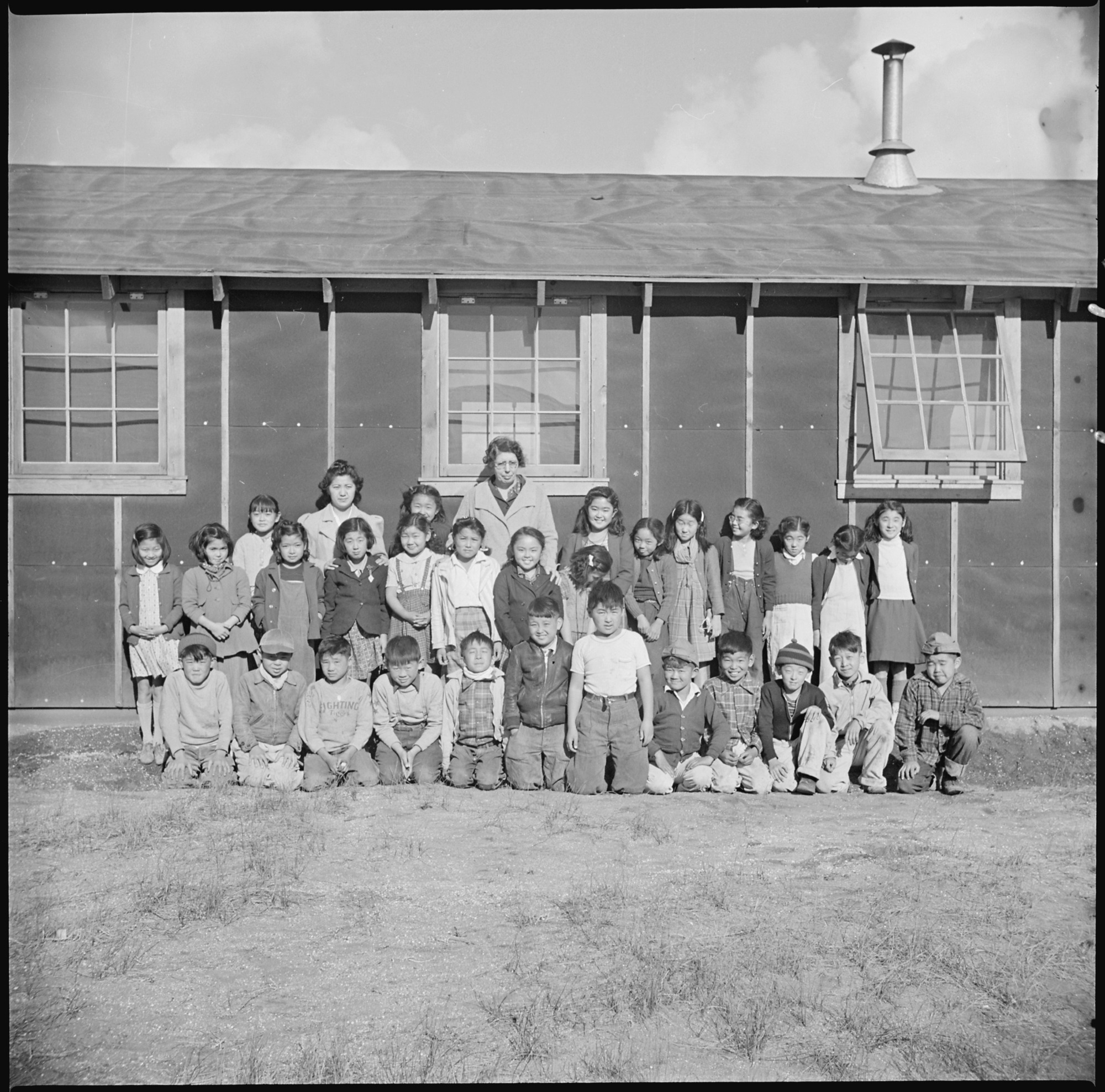 Low fifth grade pupils and their teacher, Mrs. Rhoda McGarve, outside their barracks school room