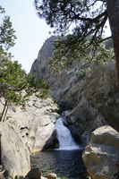 A powerful rush of water pours from a short chute into a pool within a granite canyon.