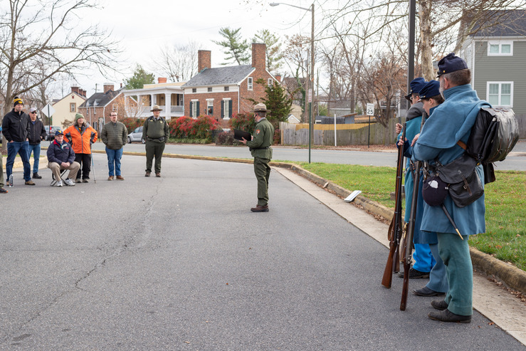 Four Union soldier living historians stand in a line while a park ranger speaks.