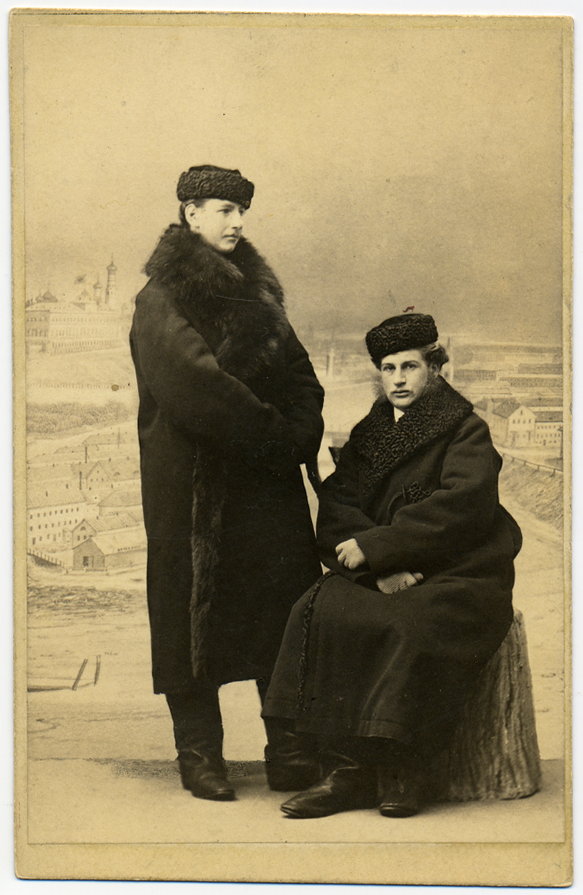 Two young man posed in thick winter jackets and hats.