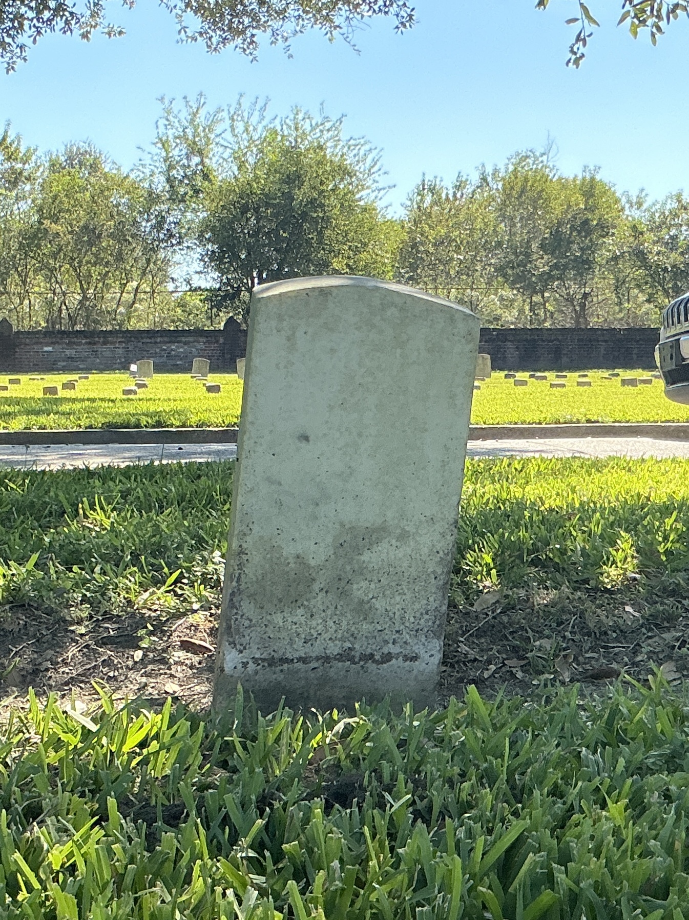 Back of historic upright marble headstone with recessed shield face.