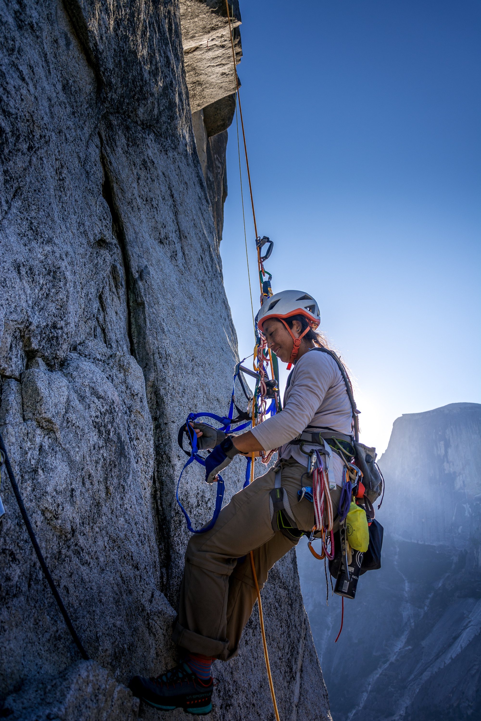 Climber ascends a rope early morning with Half Dome in the background at Washington Column.