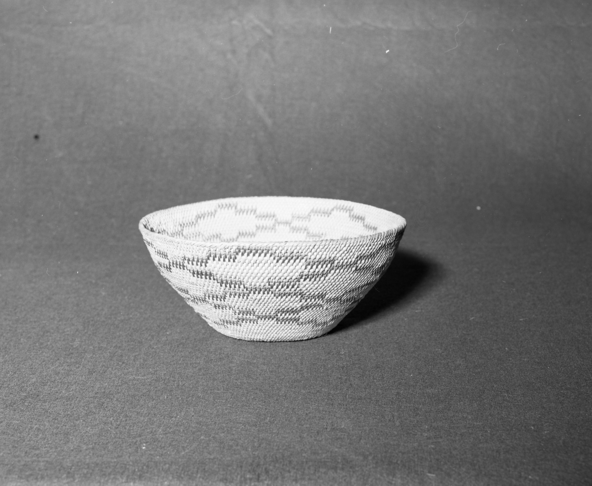 Mrs. Donal Segerstrom Collection. Object: Miwok basket. Dimensions: 9-7/8 x 4". Materials: Redbud; split shoot; probably also redbud. Technology: Single rod, overstitched rim, fag ends trimmed on work face, moving ends trimmed on interior. Photographed by Michael Dixon. Catalogued by Craig Bates and Barbara Beroza. Yosemite Collections, National Park Service. 1/83.