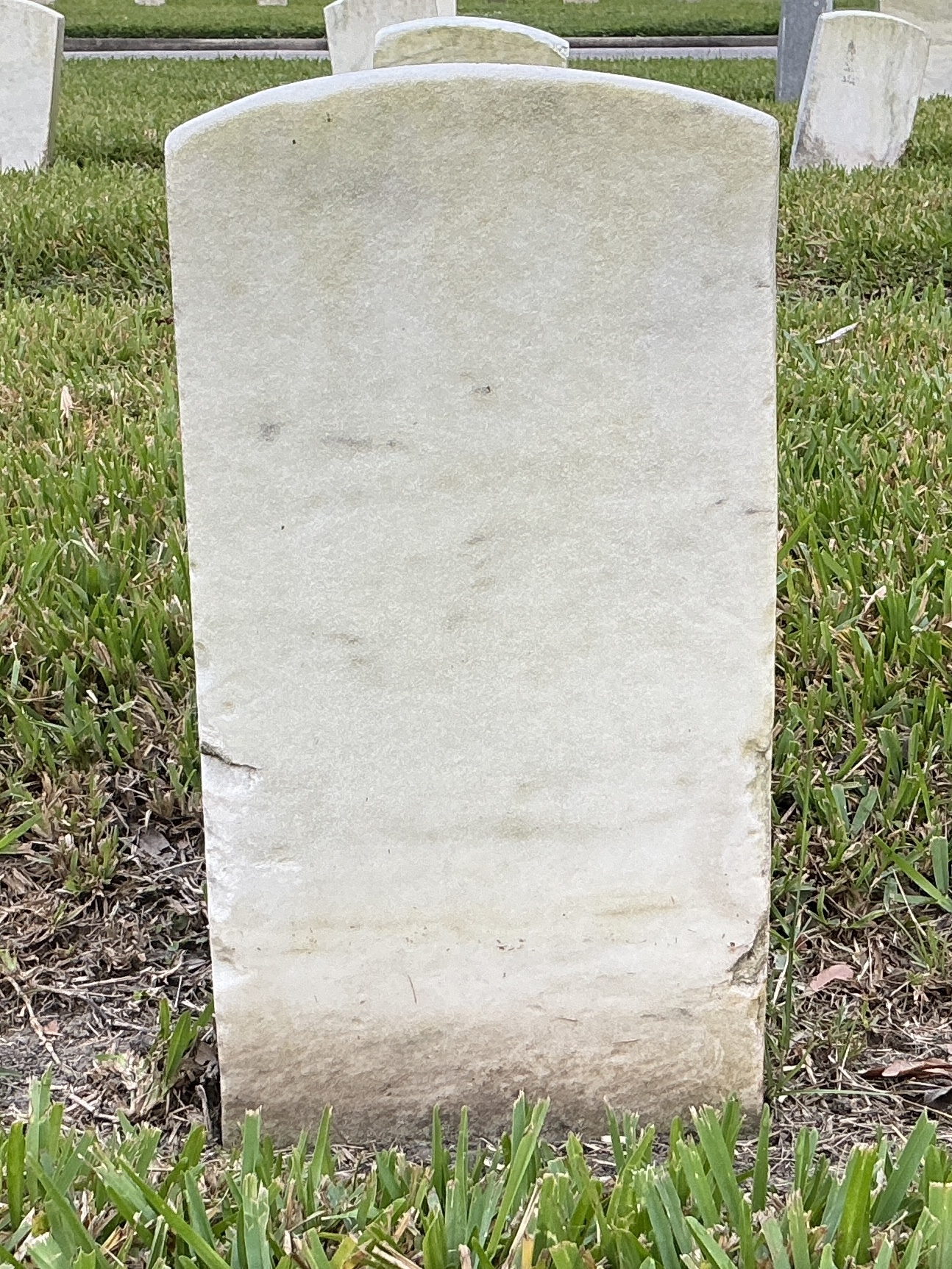 Back of historic upright marble headstone with recessed shield face.
