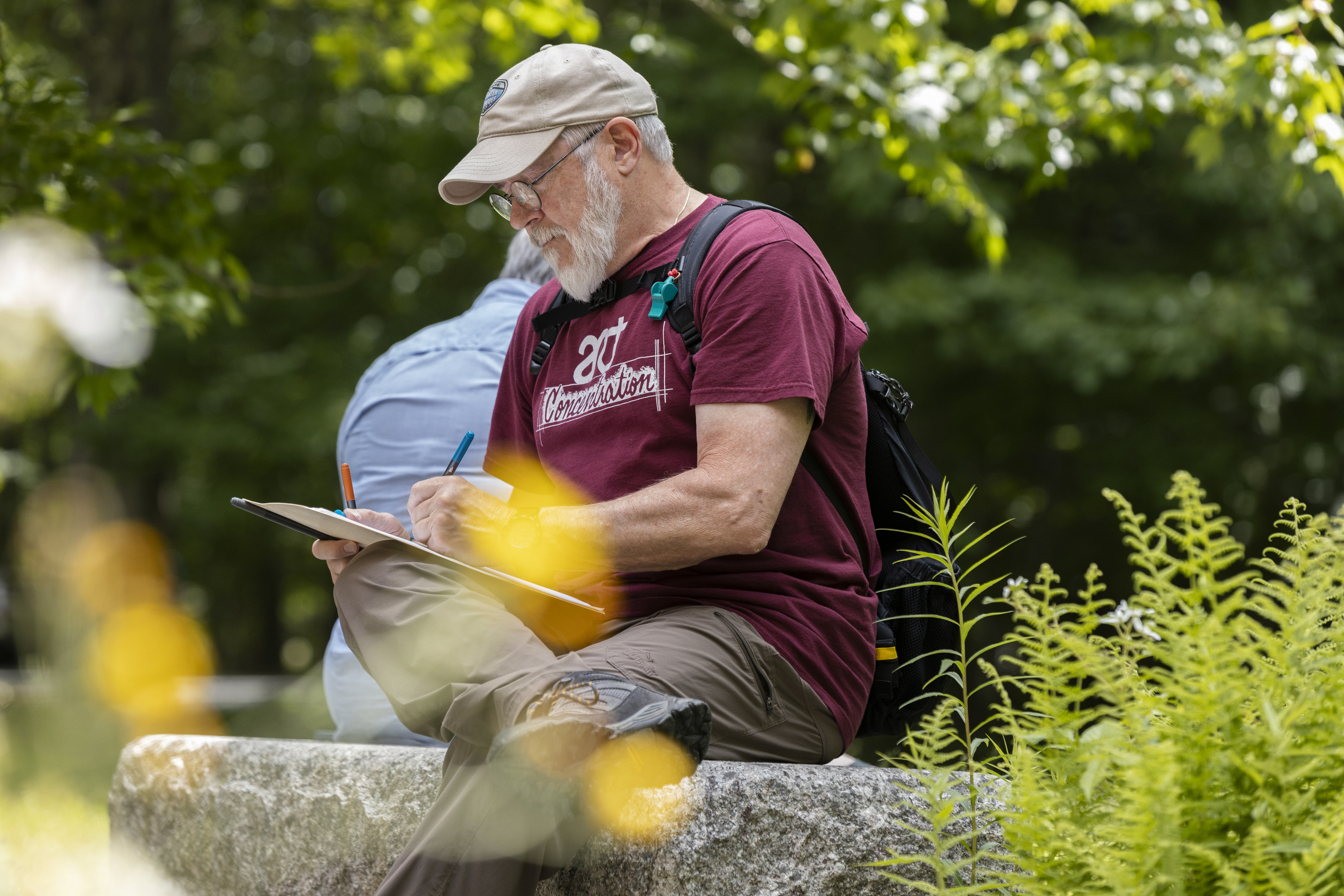 Person sketching on a clipboard while sitting on a stone bench in Sieur de Mont.