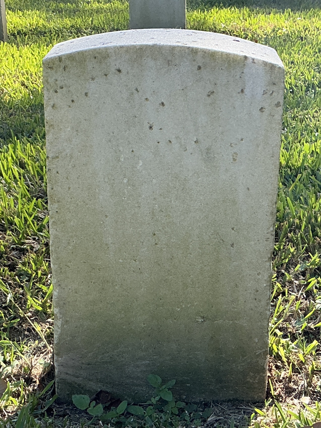 Back of historic upright marble headstone with recessed shield face.