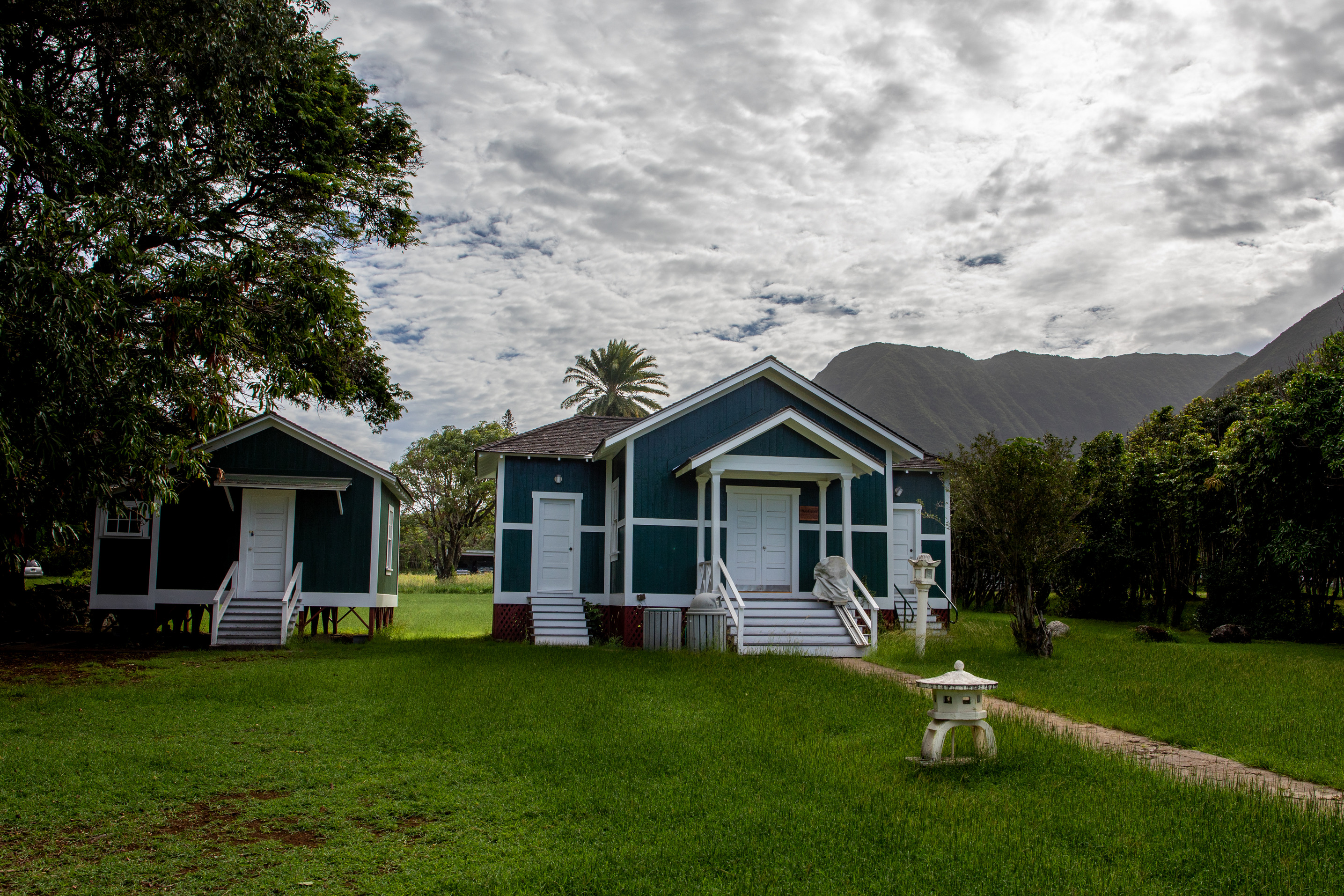 Two teal buildings with white doors and framing and a darker, shingled roof. 