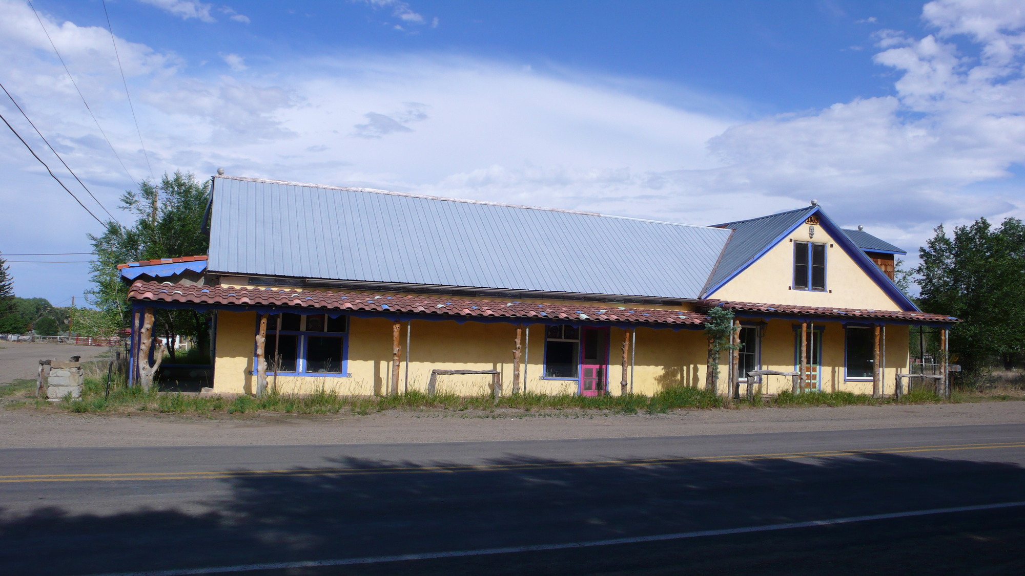 A yellow building with a blue roof beside a road.