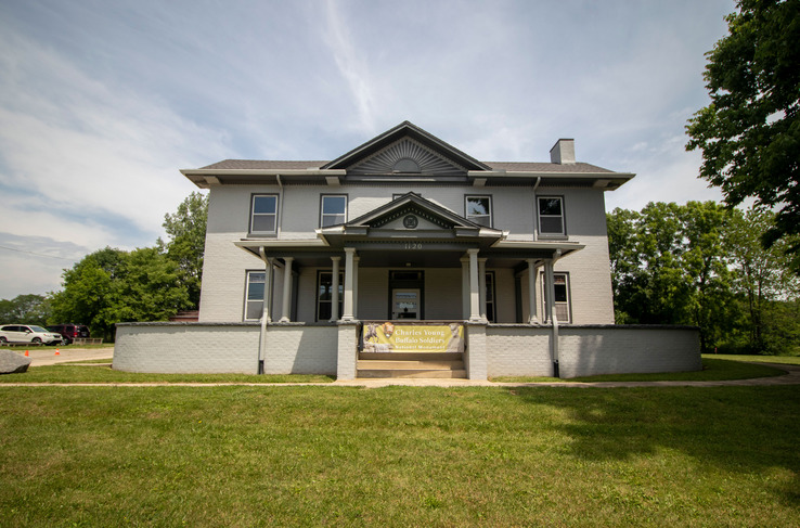 A large, two-story home with several windows and a green lawn in front.