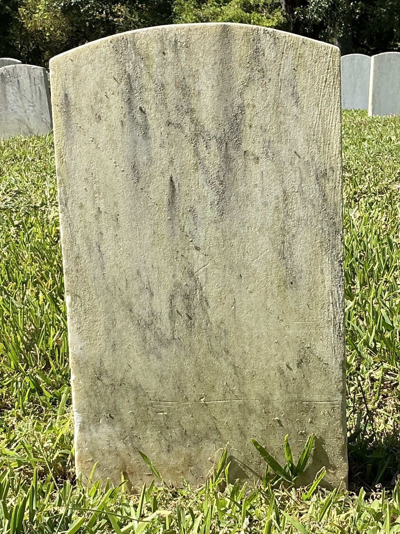 Back of historic upright marble headstone with recessed shield face.