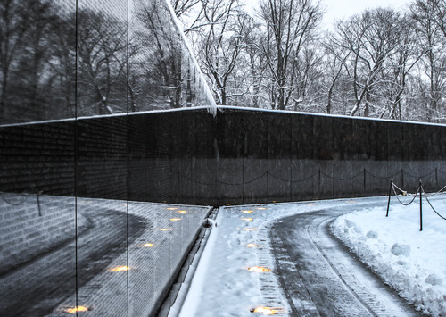 Wall of the Vietnam War Memorial, lights, and sidewalks reflecting on the other wall as they meet
