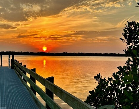 Sunset from Apollo with strong orange in the ski and being reflected in the water below. Boardwalk visible. 