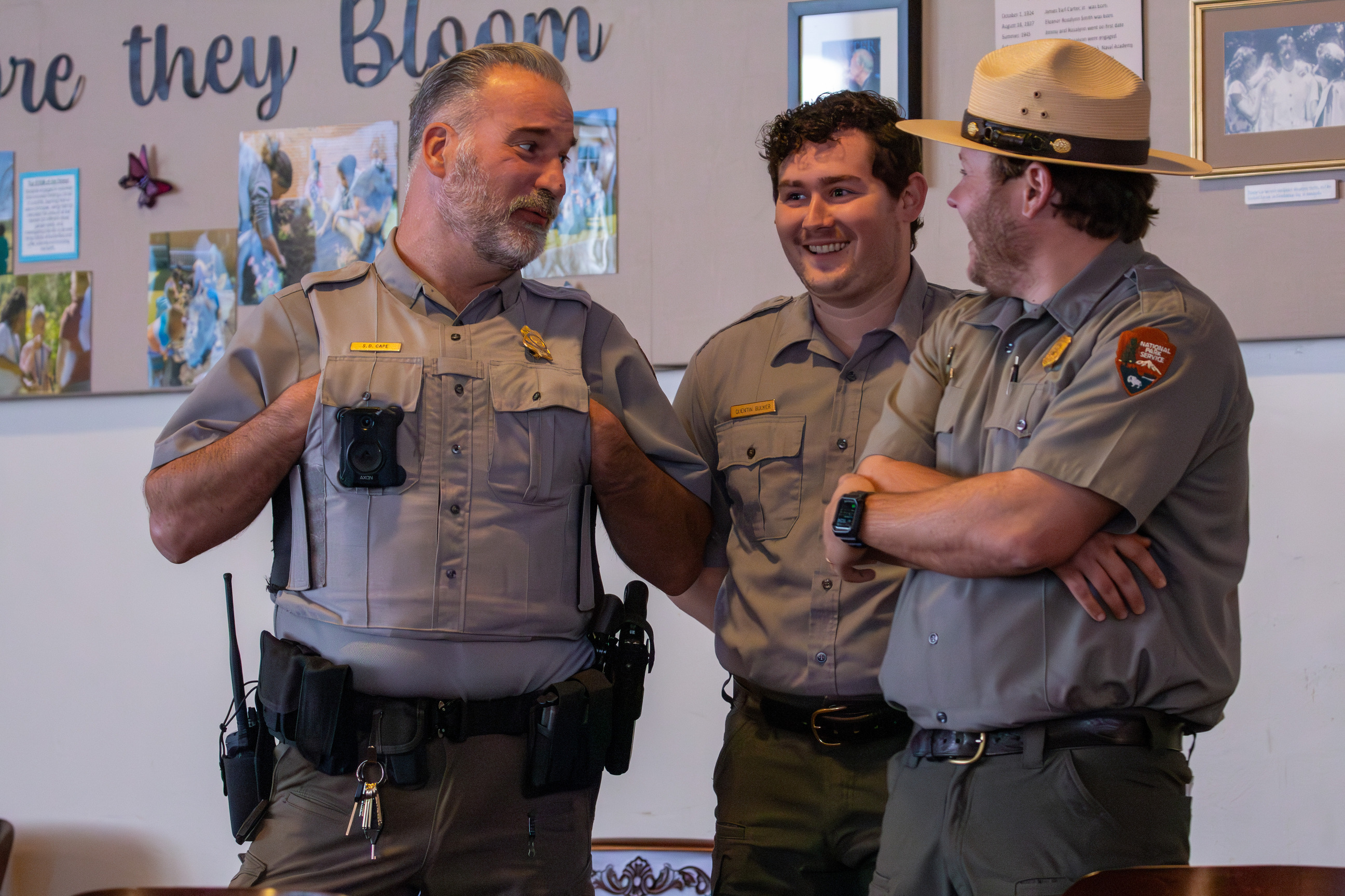 Two park rangers and one law enforcement officer standing, laughing, and talking.