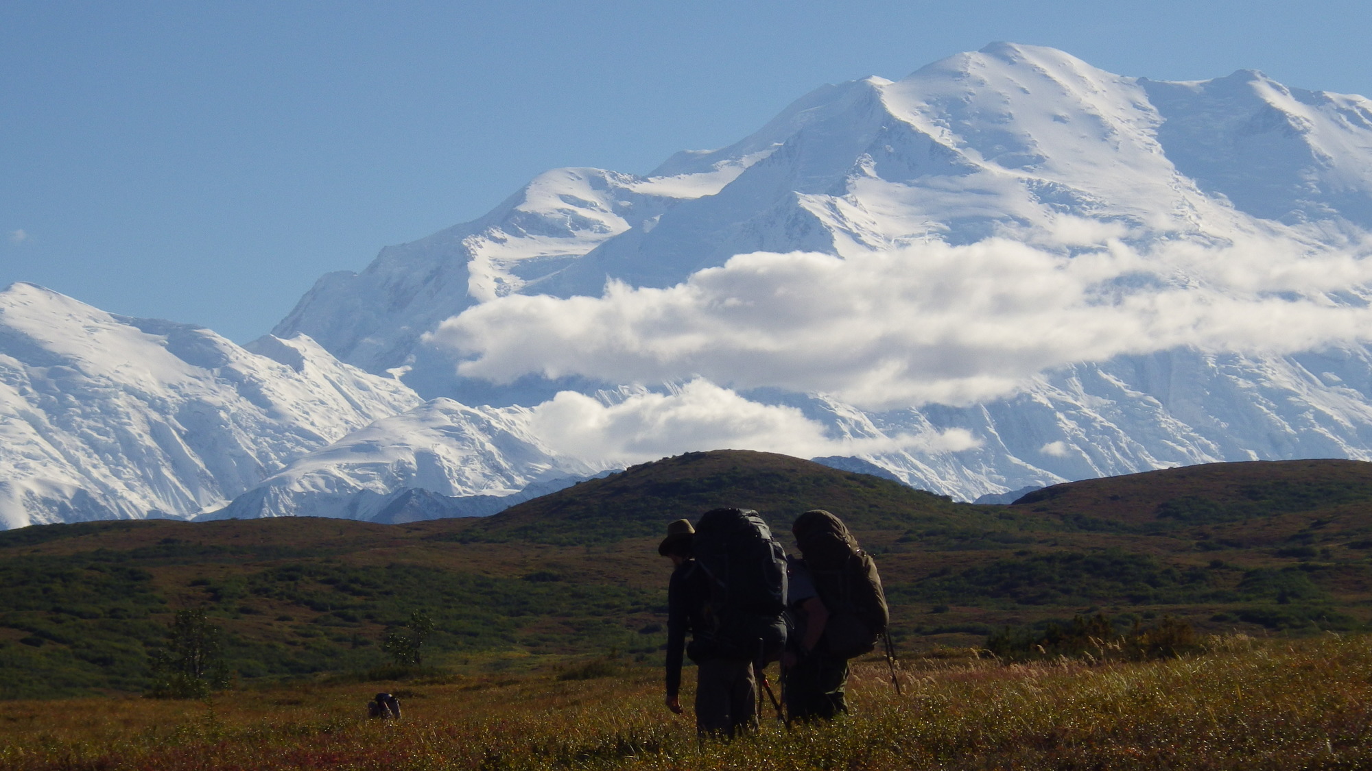 two backpackers looking at a huge snowy mountain
