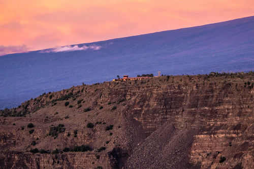 Low-rise buildings sit on the crumbling edge of a volcanic crater