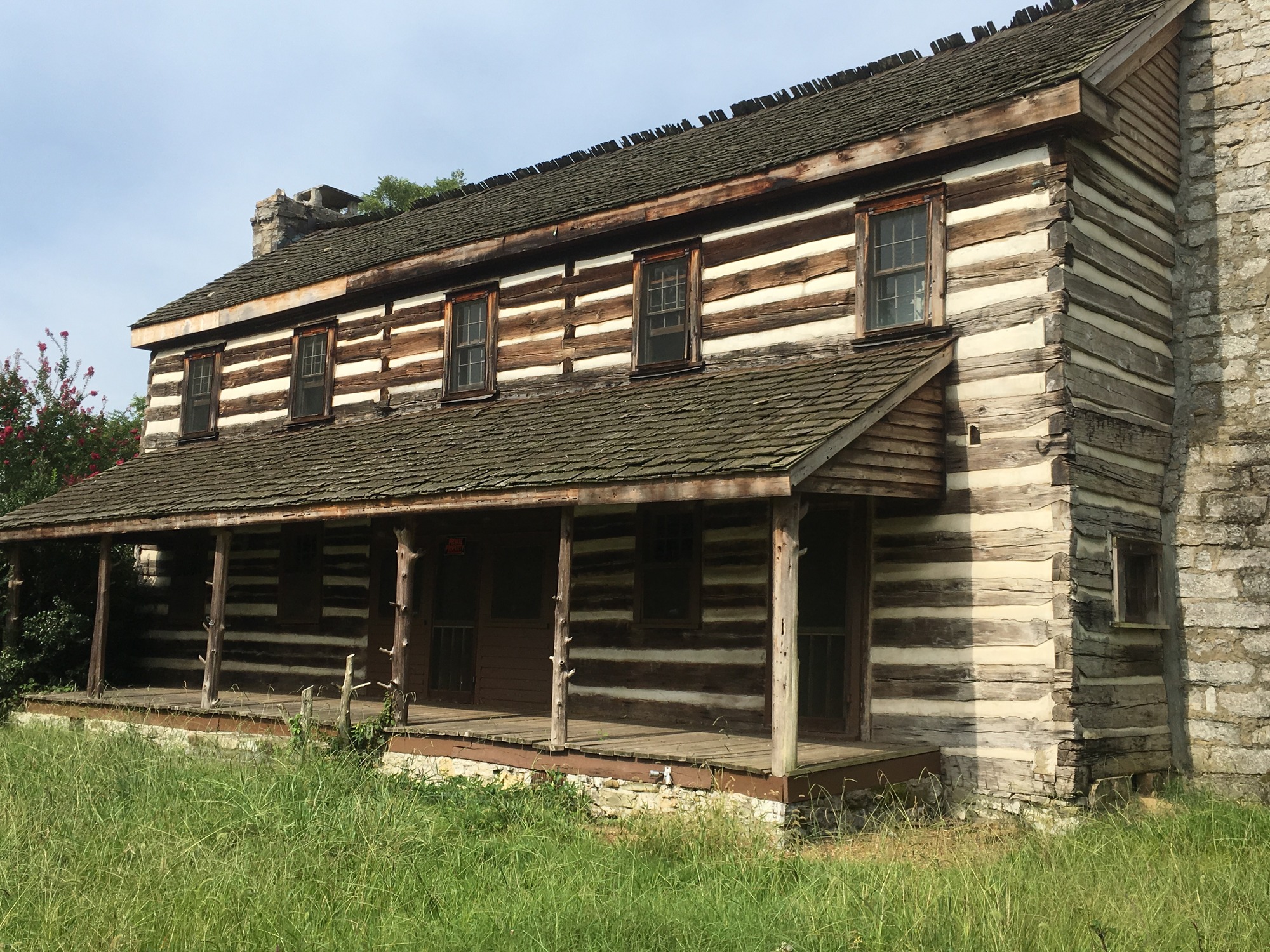 A log cabin in the middle of a grassy field.