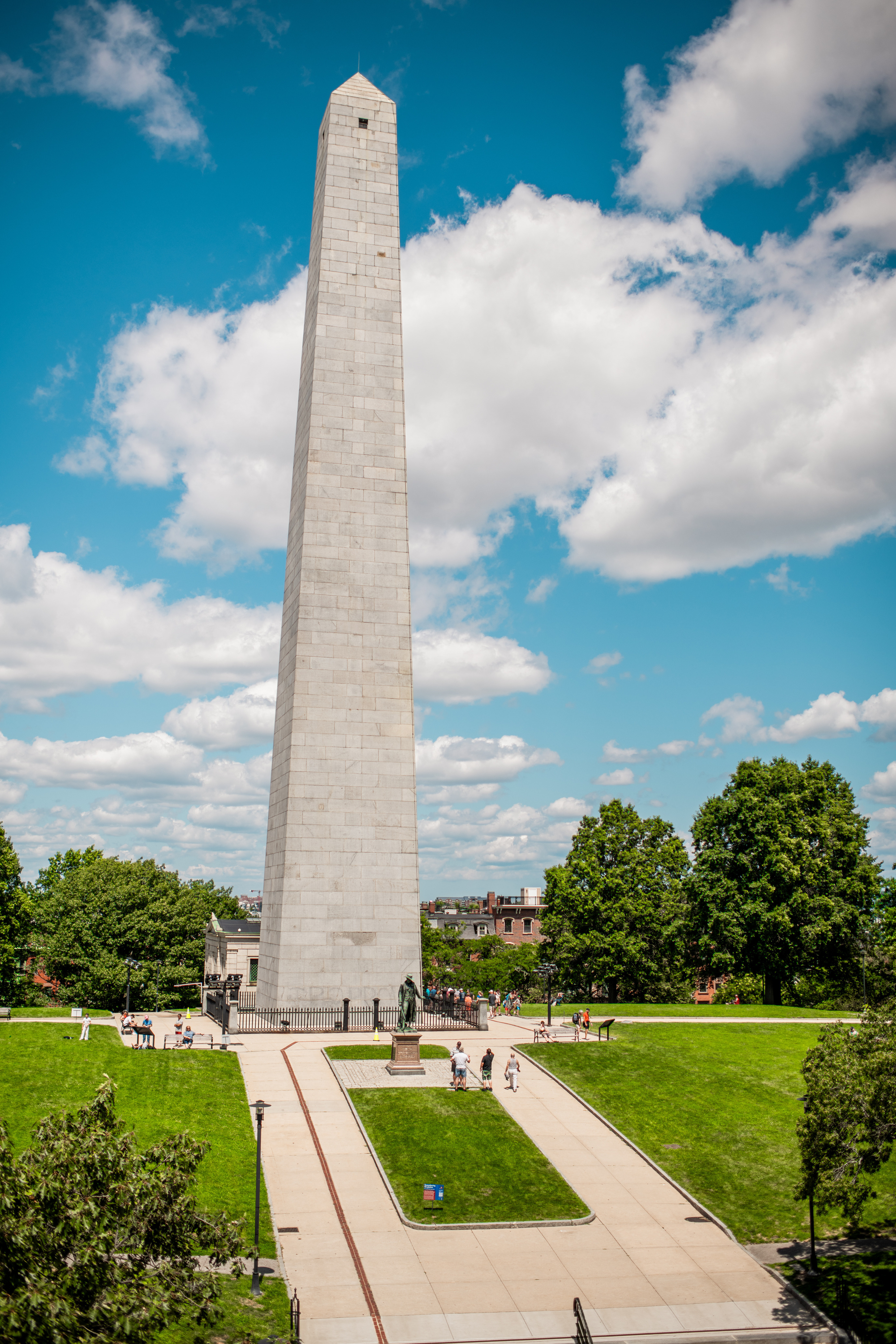 Bunker Hill monument sitting atop the hill surrounded by leafy green trees
