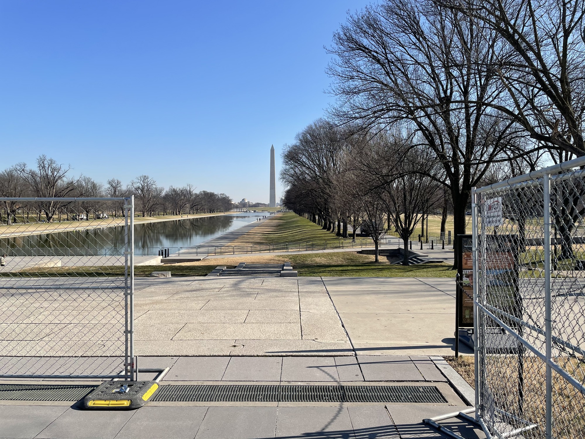 An open event fence leading to a long reflecting pool and the Washington Monument in the distance