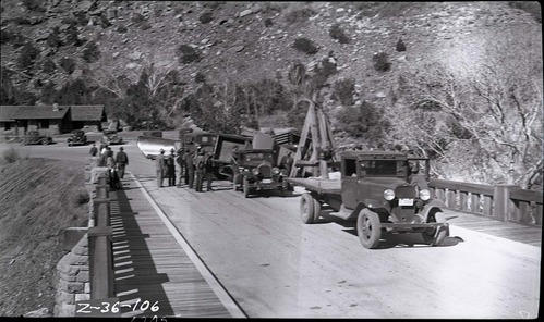 Vehicle accident on the Virgin River bridge of the Zion-Mt. Carmel Highway. View of overturned truck that has just been removed from the bridge abutment and righted by workers, tow truck, and other equipment.
