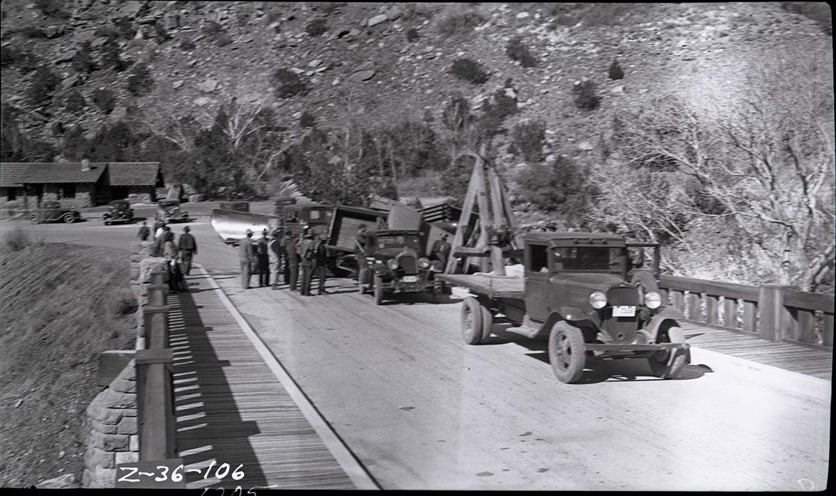 Vehicle accident on the Virgin River bridge of the Zion-Mt. Carmel Highway. View of overturned truck that has just been removed from the bridge abutment and righted by workers, tow truck, and other equipment.