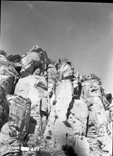 Mountain rescue, man stands above the crack where West Temple climb was made. Another man sits at base of wall.