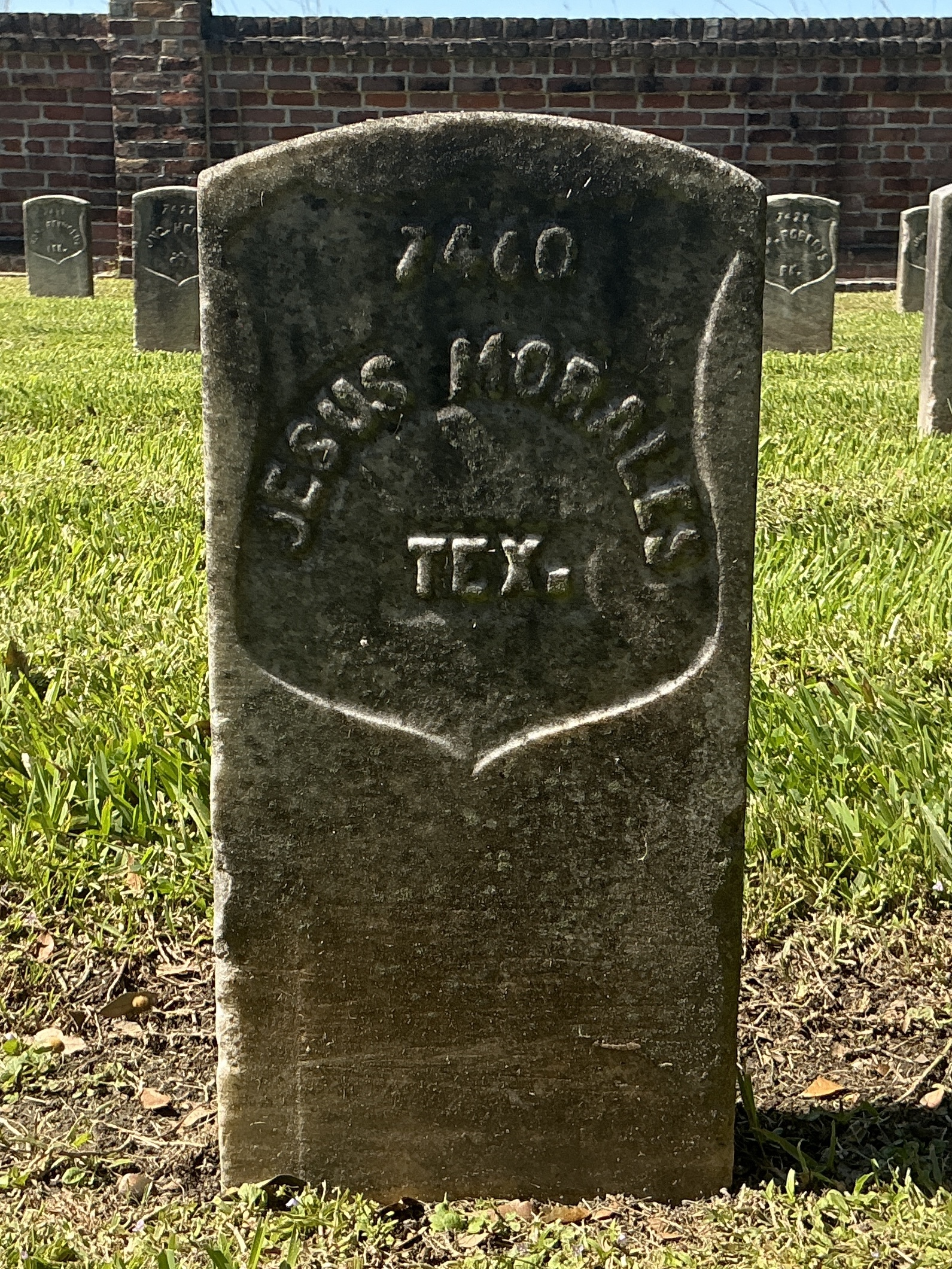 Front of historic upright marble headstone with recessed shield with recessed lettering face.