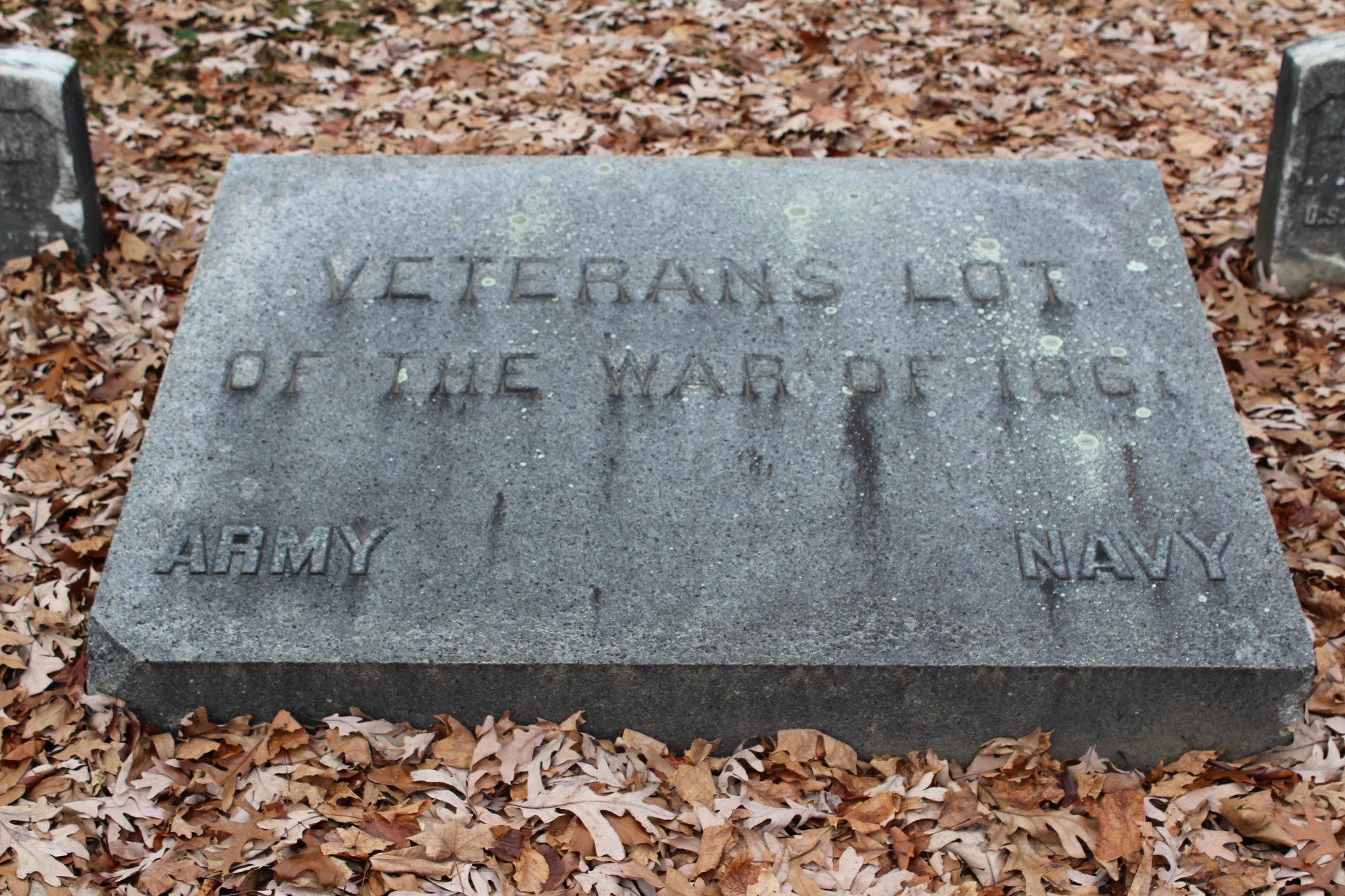 Granite grave in the ground with the text Veterans Lot of the War of 1861. 