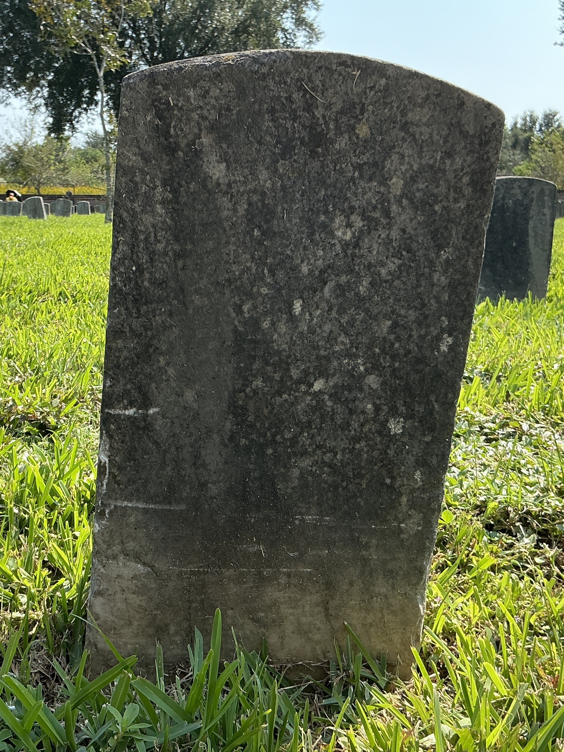 Back of historic upright marble headstone with recessed shield face.