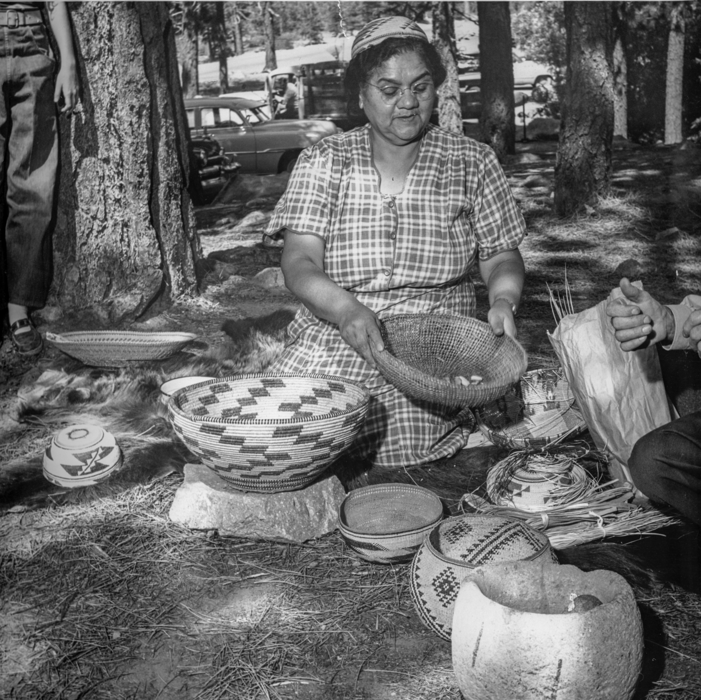 A woman sits and holds a basket with acorns in it