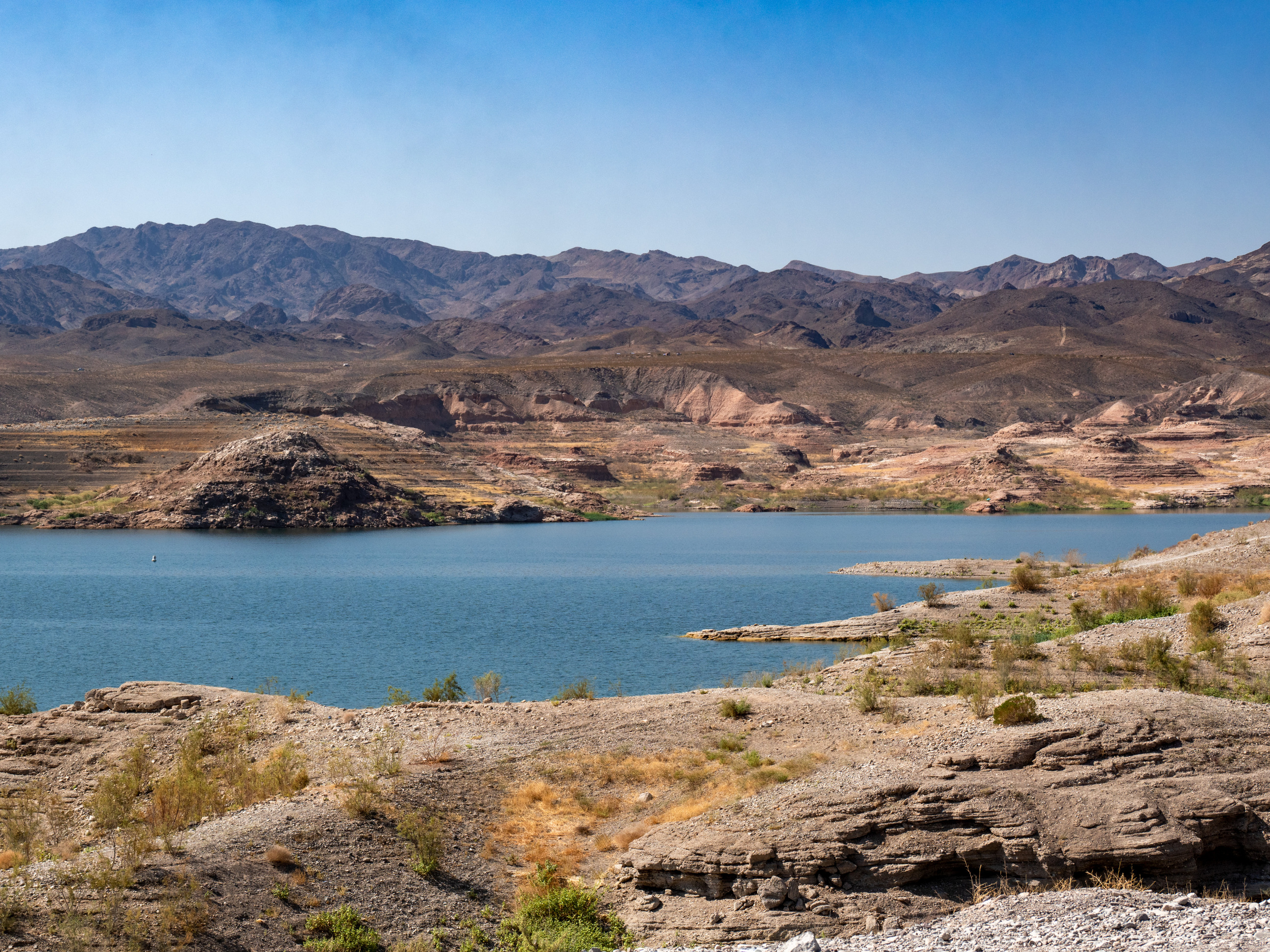 desert with bushes foreground, lake midground, mountains and hills in distance