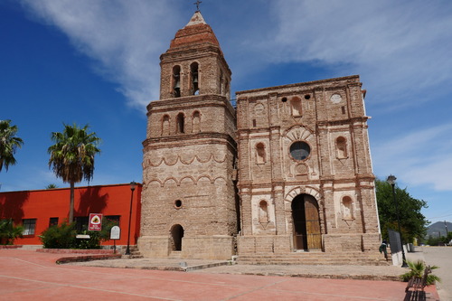 A large brick church with a belltower and an arched wooden door