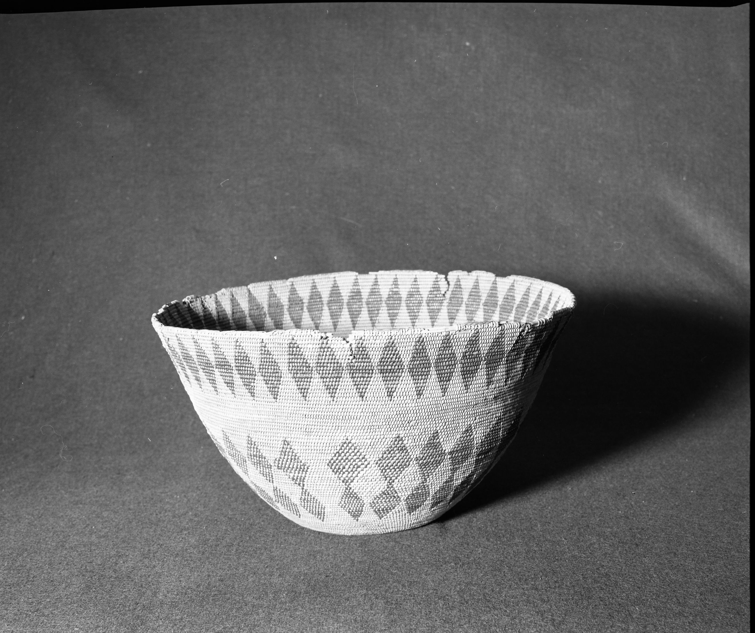 Marie Rozier Collection, Catalog No. 2. Object: Miwok cooking basket. Dimensions: 15 x 8 1/4". Materials: Bracken fern, unidentified split shoot, (possibly maple). Technology: 3 rod foundation, spaced stitching, fag ends trimmed on work face, moving ends trimmed on interior, leftward coil direction, clockspring start with 1/4" diameter hole remaining. Rim finish nearly gone but of slanted type. Never used. Collection History: Bought from Evelena Cox in Tuolumne about 1910 by Annie Teague. Photographed by Michael Dixon in December 1982. Photographed by Michael Dixon in December 1982. Catalogued by Craig Bates and Barbara Beroza. Yosemite Collections, National Park Service.