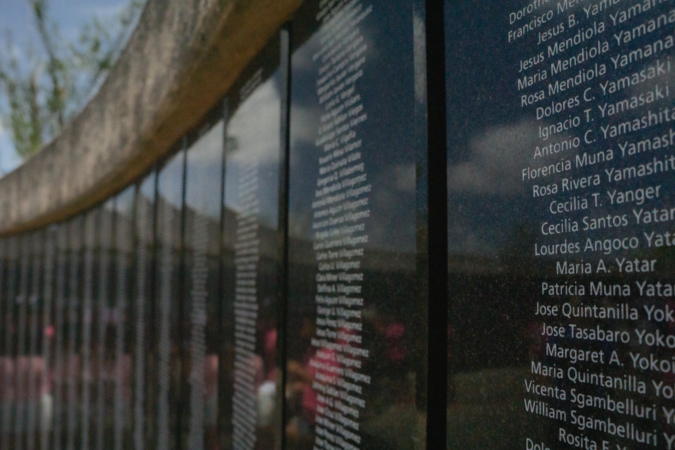 Close up shot of a curved wall covered in black plaques with names engraved on them.