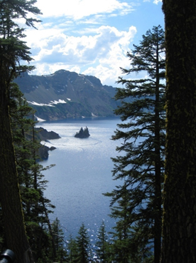 A small island pokes out of the lake, surrounded by tall peaks and pines.